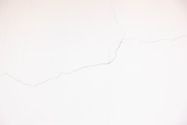 A white wall with visible thin cracks running across its surface.