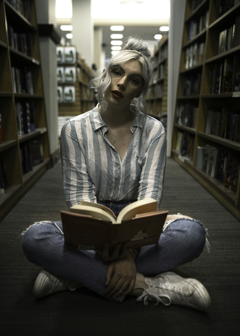 woman sitting near book rack