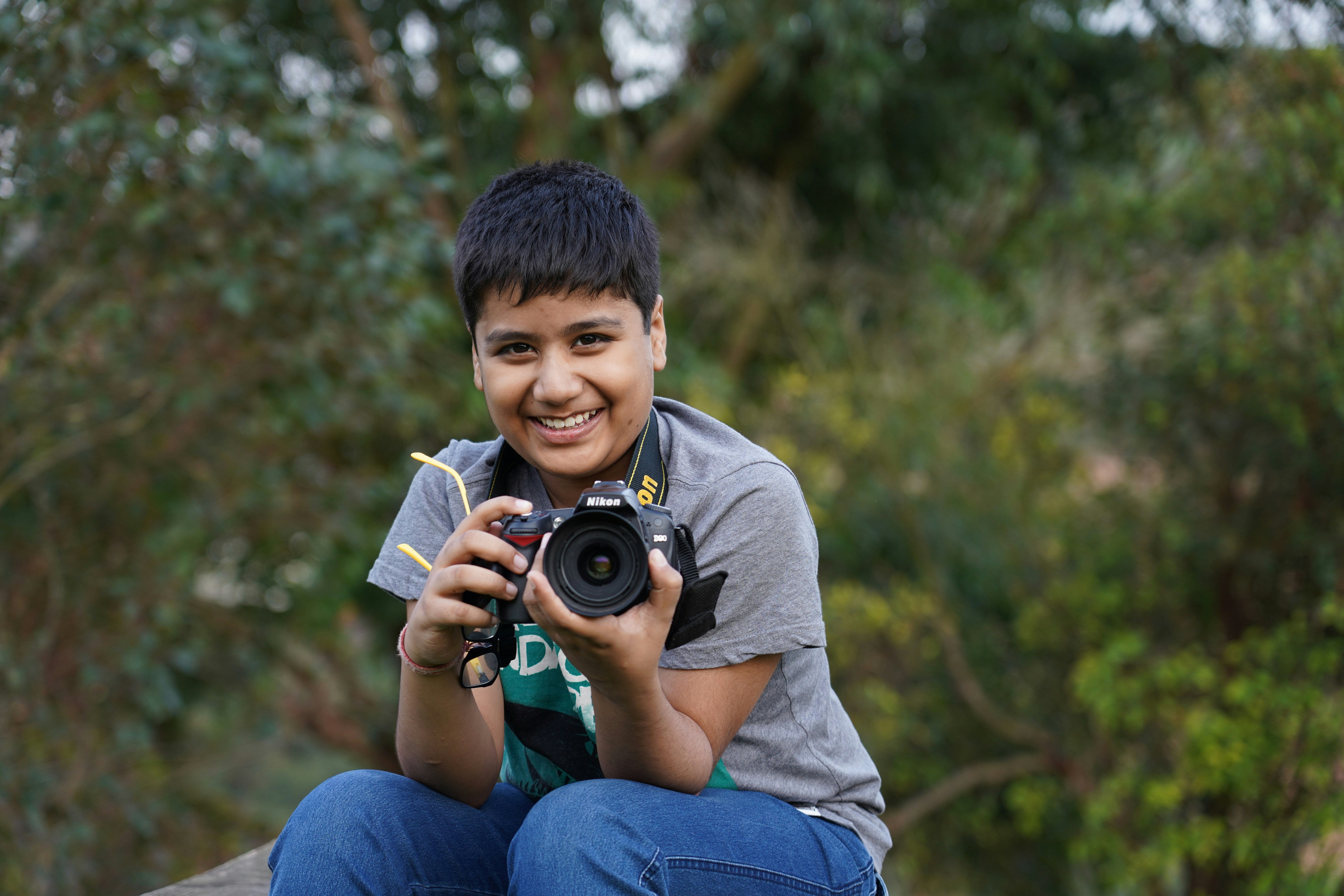 smiling boy holds black DSLR camera