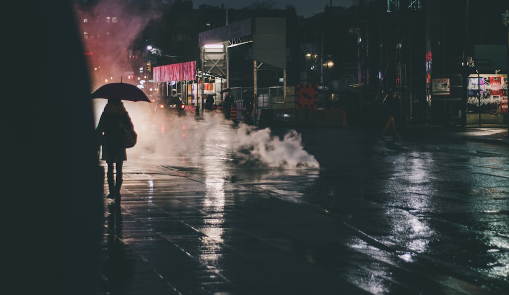 silhouette photography of person walking holding umbrella