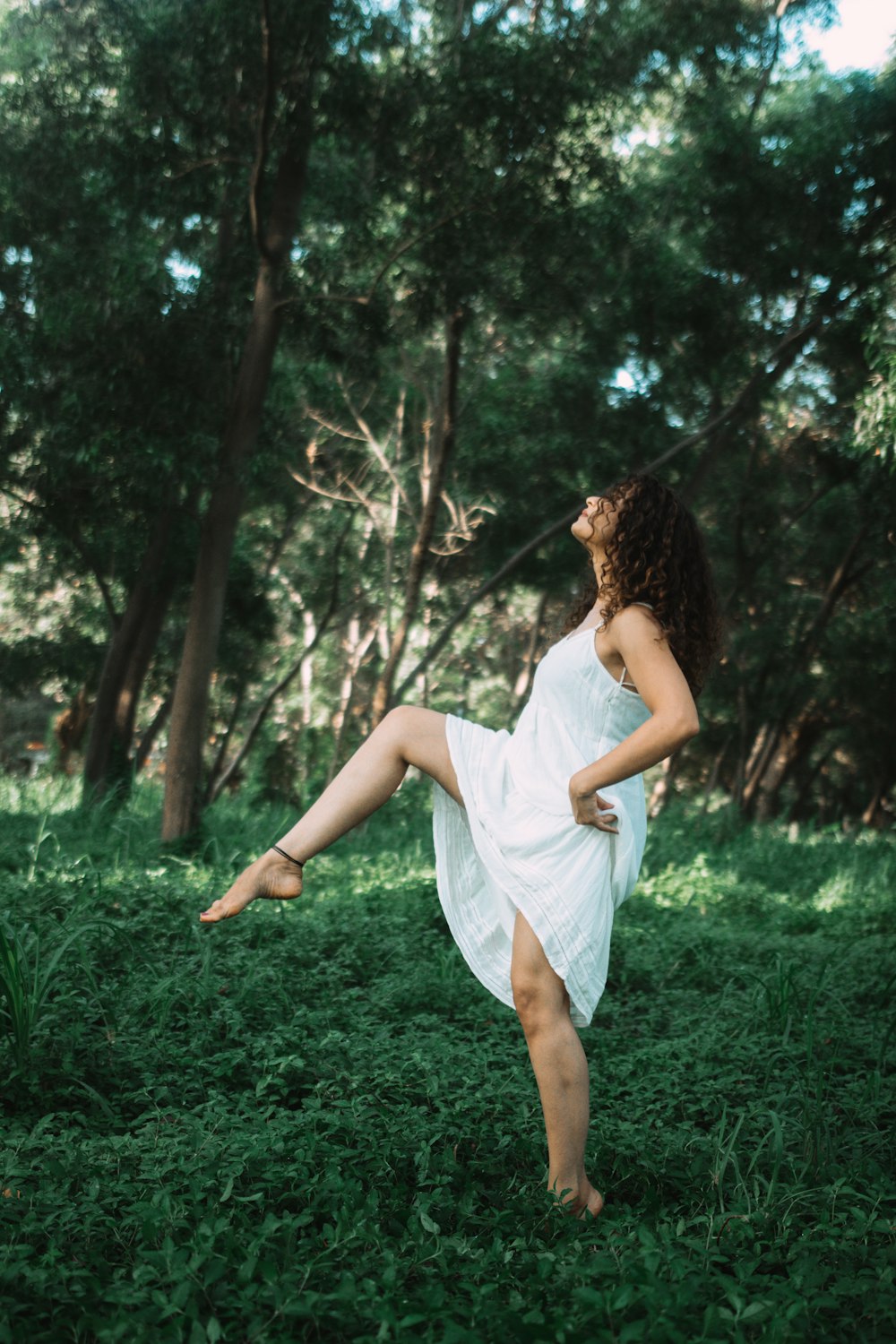 donna che cammina sull'erba verde vicino agli alberi