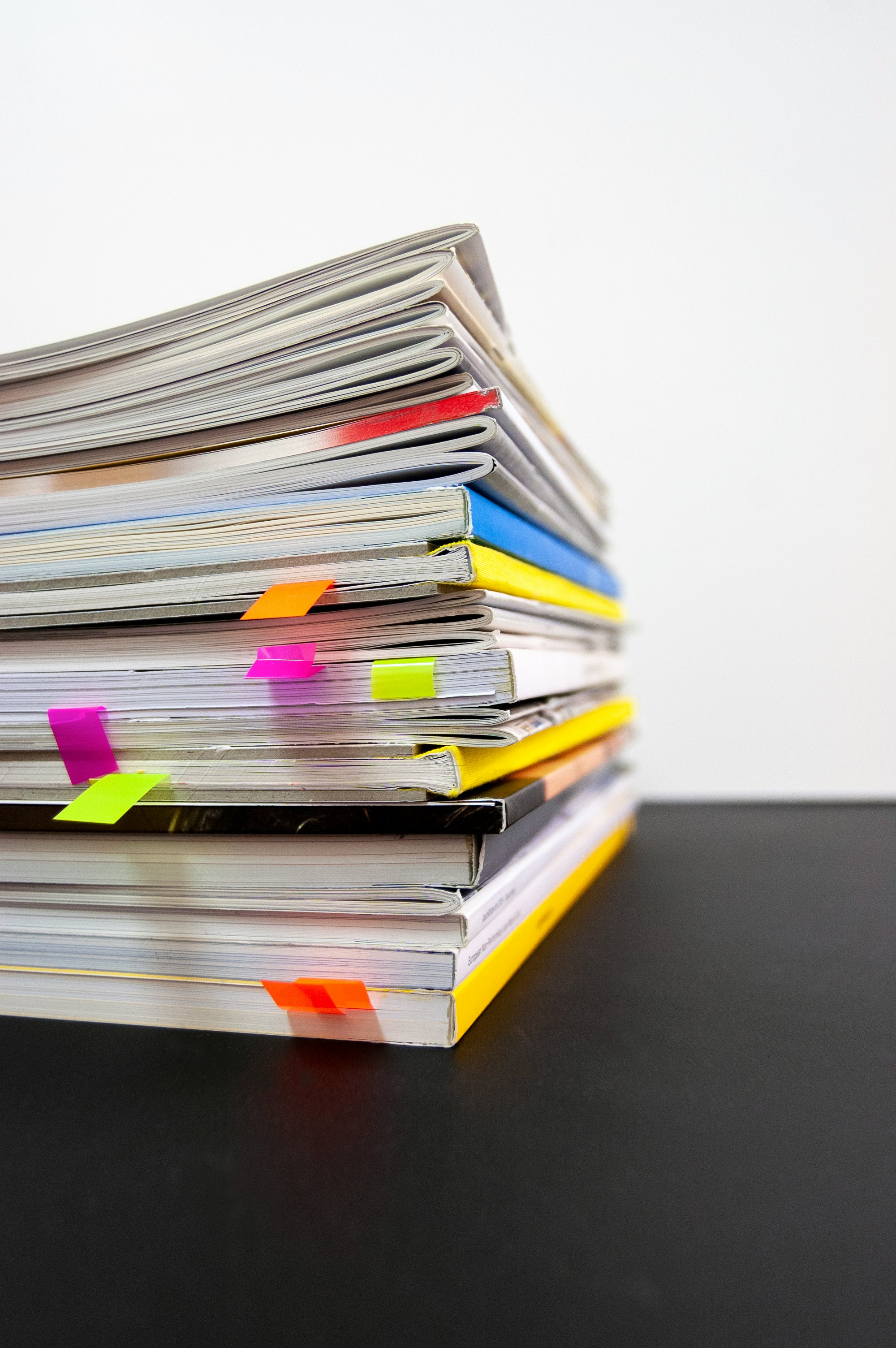 stack of paperback books with neon bookmarks