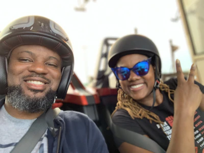 Close-up of a passenger holding onto the driver, both wearing casual clothes and helmets.