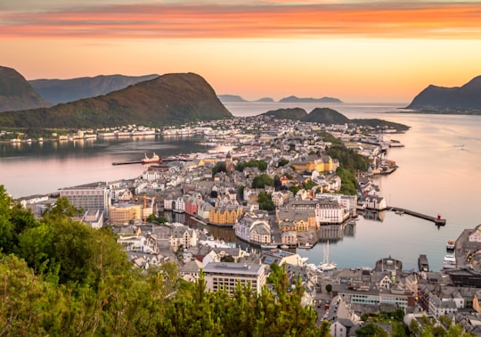 photography of gray and white buildings beside shore during daytime in Ålesund Norway