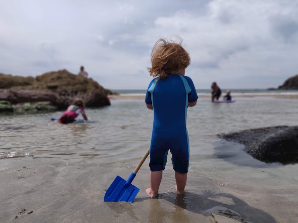 toddler holding plastic spade on shore