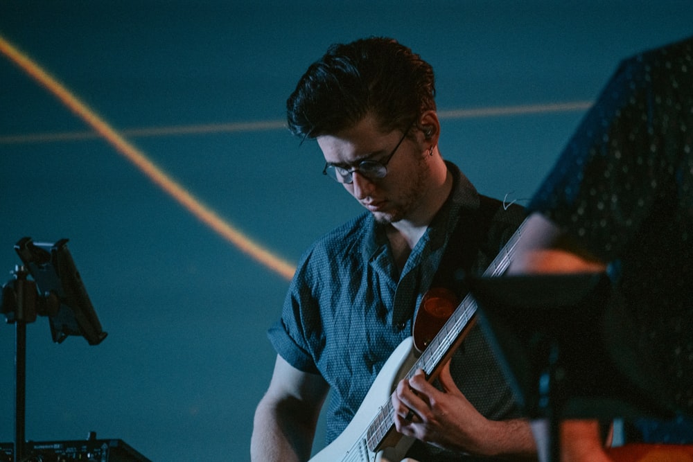 man wearing gray shirt playing guitar