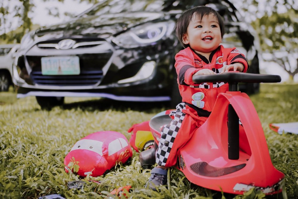 boy riding wiggle car on grass near sedan