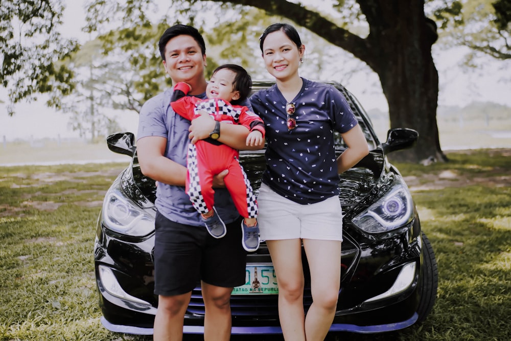 family taking photo in front of car