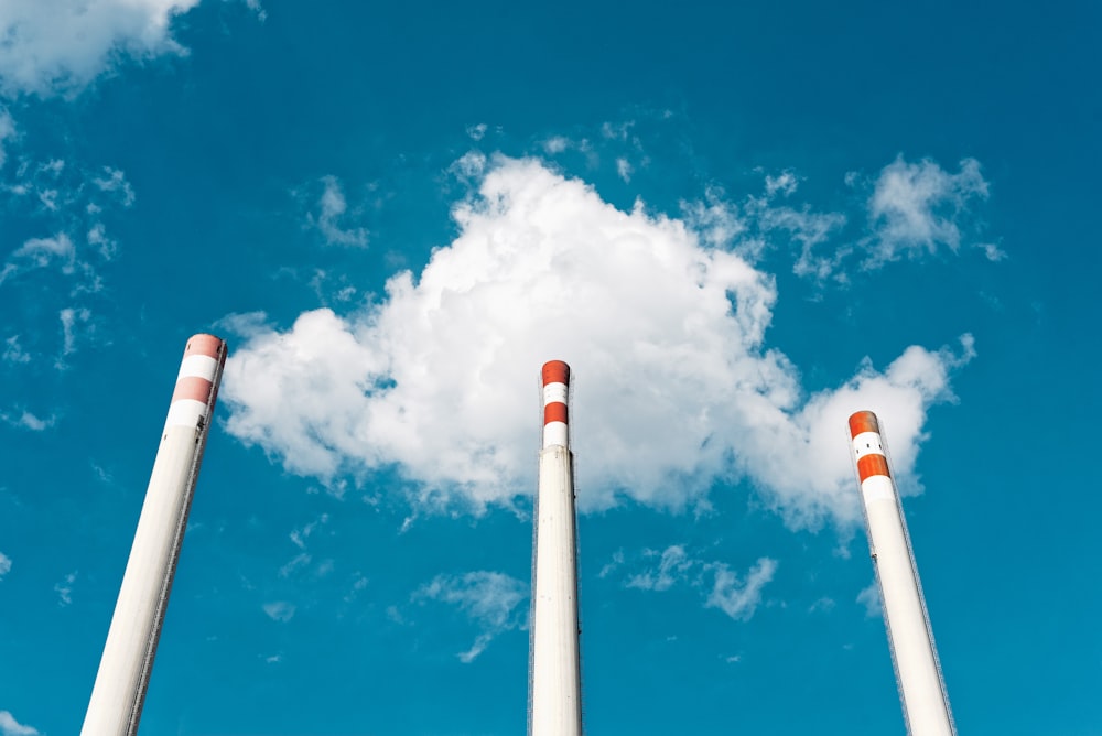 three white poles under white clouds and blue sky during daytime