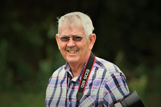 A cheerful retired man with a camera exploring a colorful local market on his travels.
