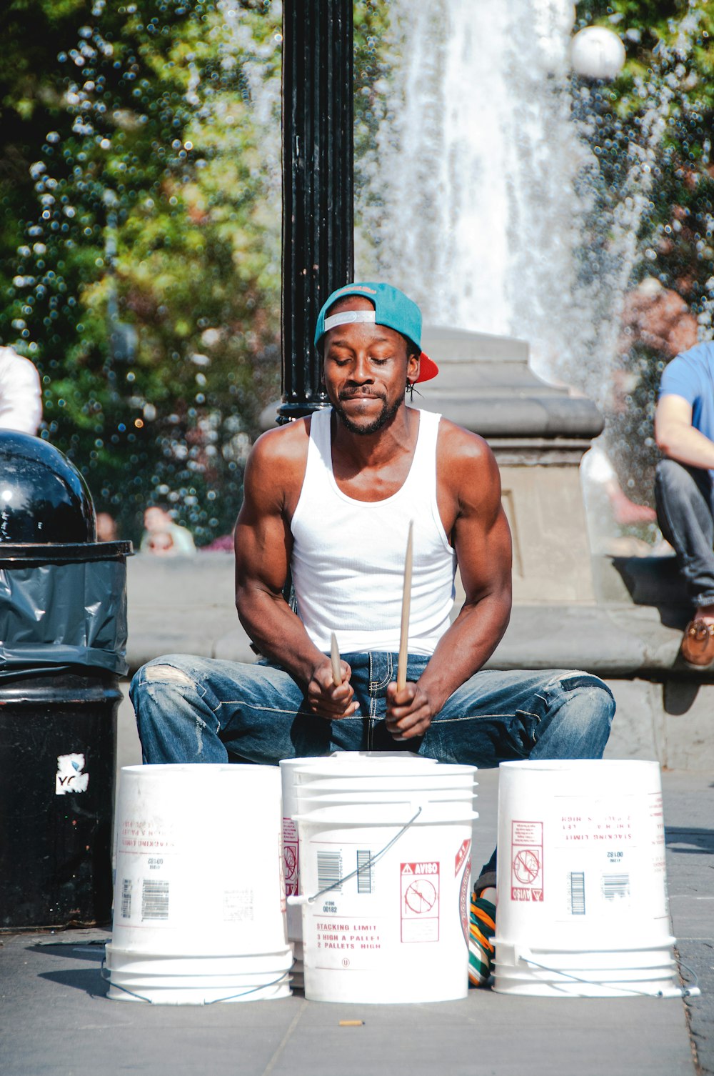 man in white tank top playing with three white plastic buckets