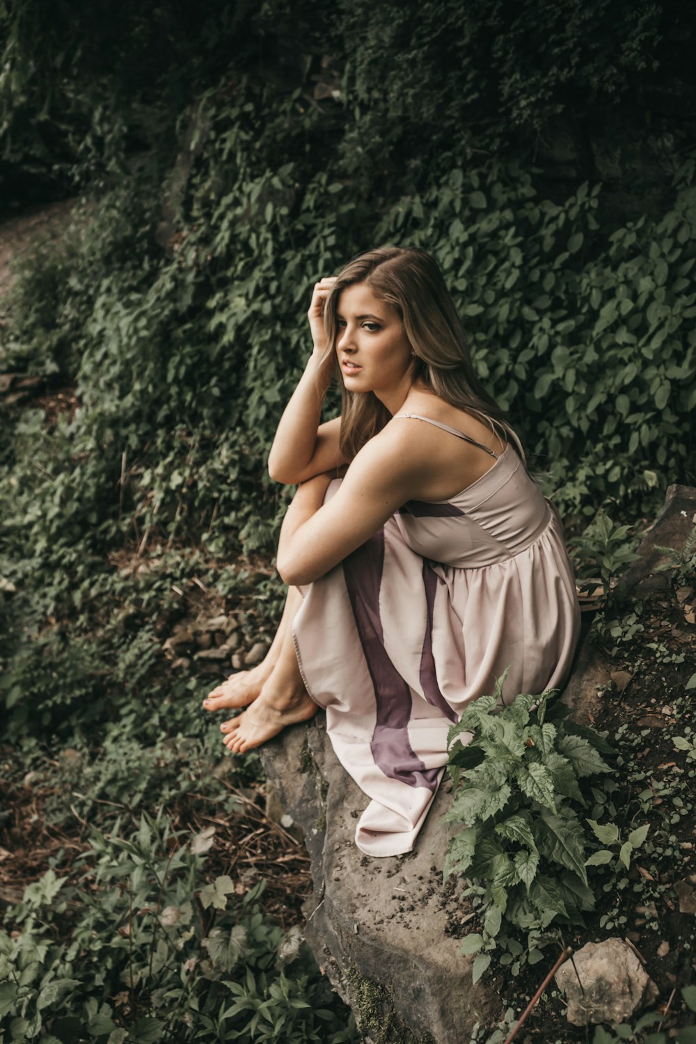 woman in gray spaghetti strap dress sitting on rock cliff