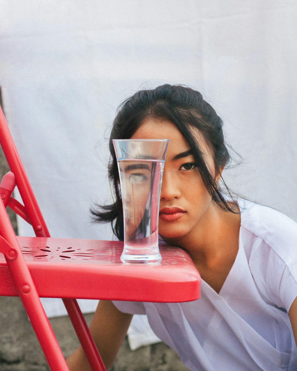 woman in white top looking through glass of water