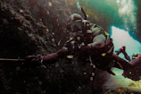 A scuba diver exploring a dramatic underwater cave illuminated by natural light.