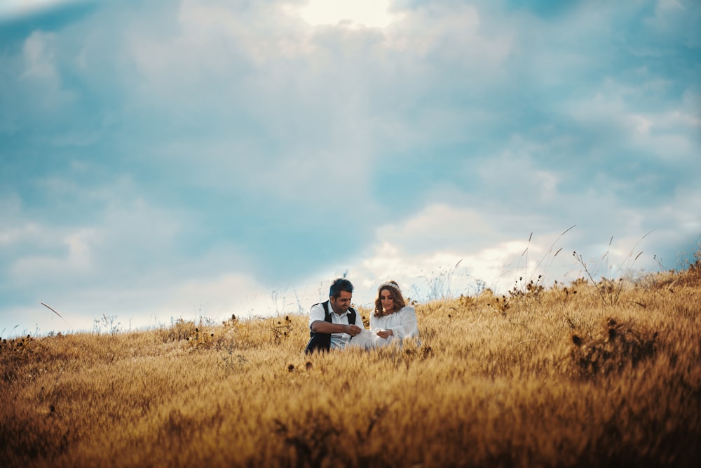 shallow focus photo of man and woman sitting on grass field during daytime