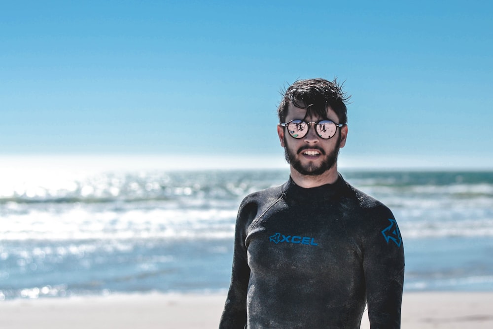 hombre en negro rashguard al lado de la playa