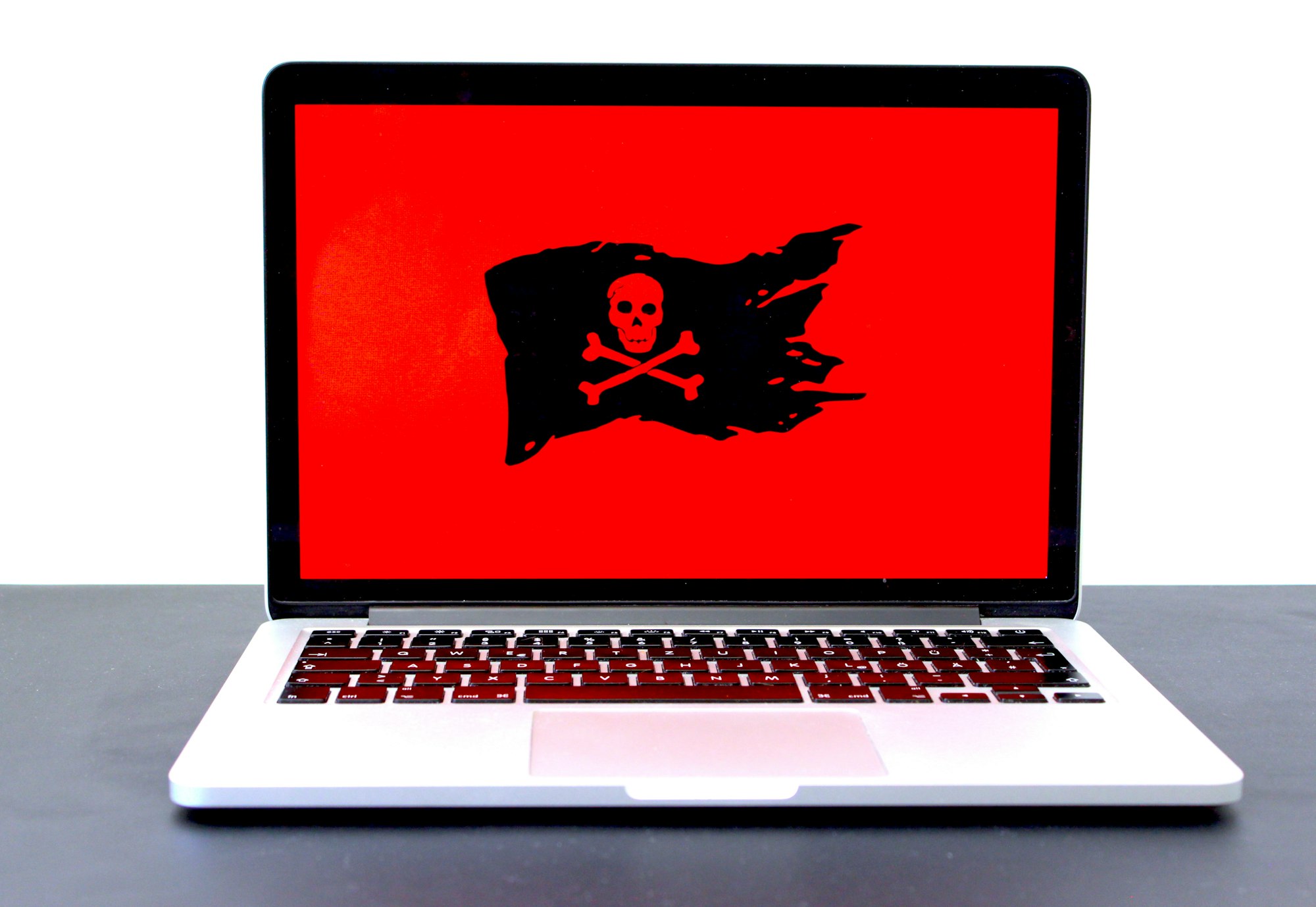 Laptop displaying a pirate flag / jolly roger on a red screen, possibly indicating malware, hackers or a different computer problem. If you like that image, consider donating at https://sharethemeal.org/donate - thanks!
