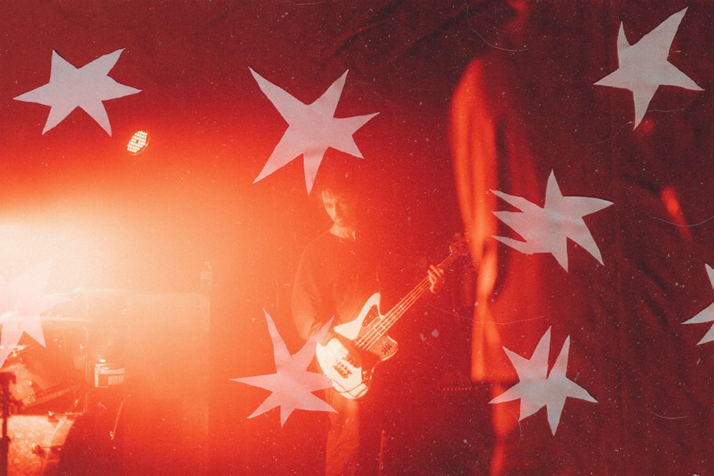 a man playing a guitar in front of a flag