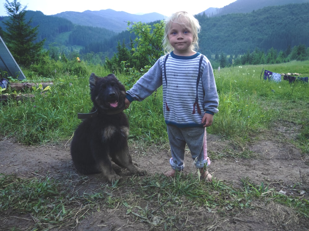 girl wearing blue striped shirt beside black dog