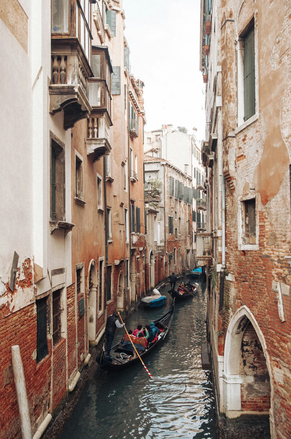 people riding on boat on canal between buildings