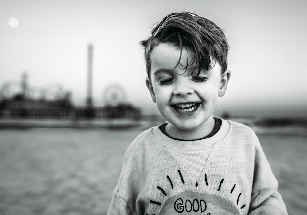 grayscale photo of smiling boy in sweater