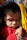 A young child with closed eyes rests their head on an adult's hand, which gently cradles the child's cheek. The child is wearing a red garment and has short, dark hair. Sunlight highlights the child's delicate facial features.