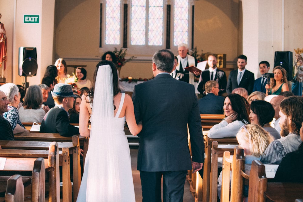 人々に囲まれた教会の中で男性と一緒に歩く花嫁