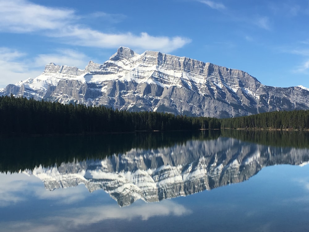 body of water with reflections of gray mountain