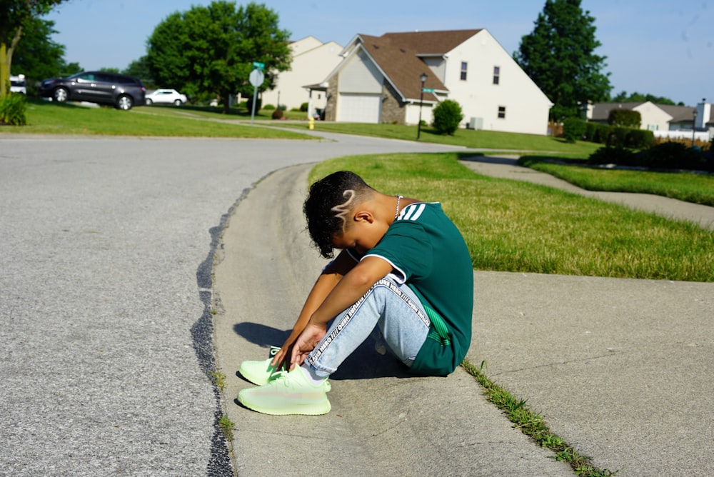 boy sits on pavement and head down