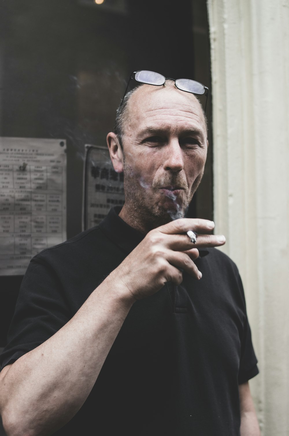 man in black polo shirt smoking cigarette
