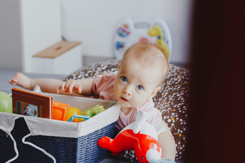 baby beside square blue wicker basket