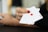 A hand with red nail polish holds two playing cards, including an ace with a diamond suit, against a blurred background.