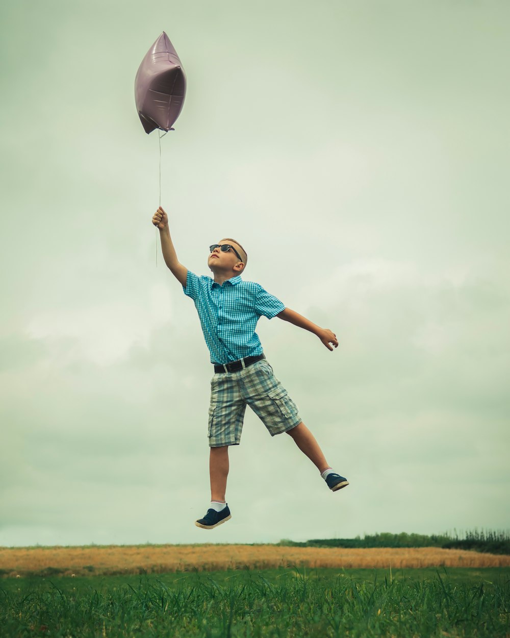 boy holding gray balloon