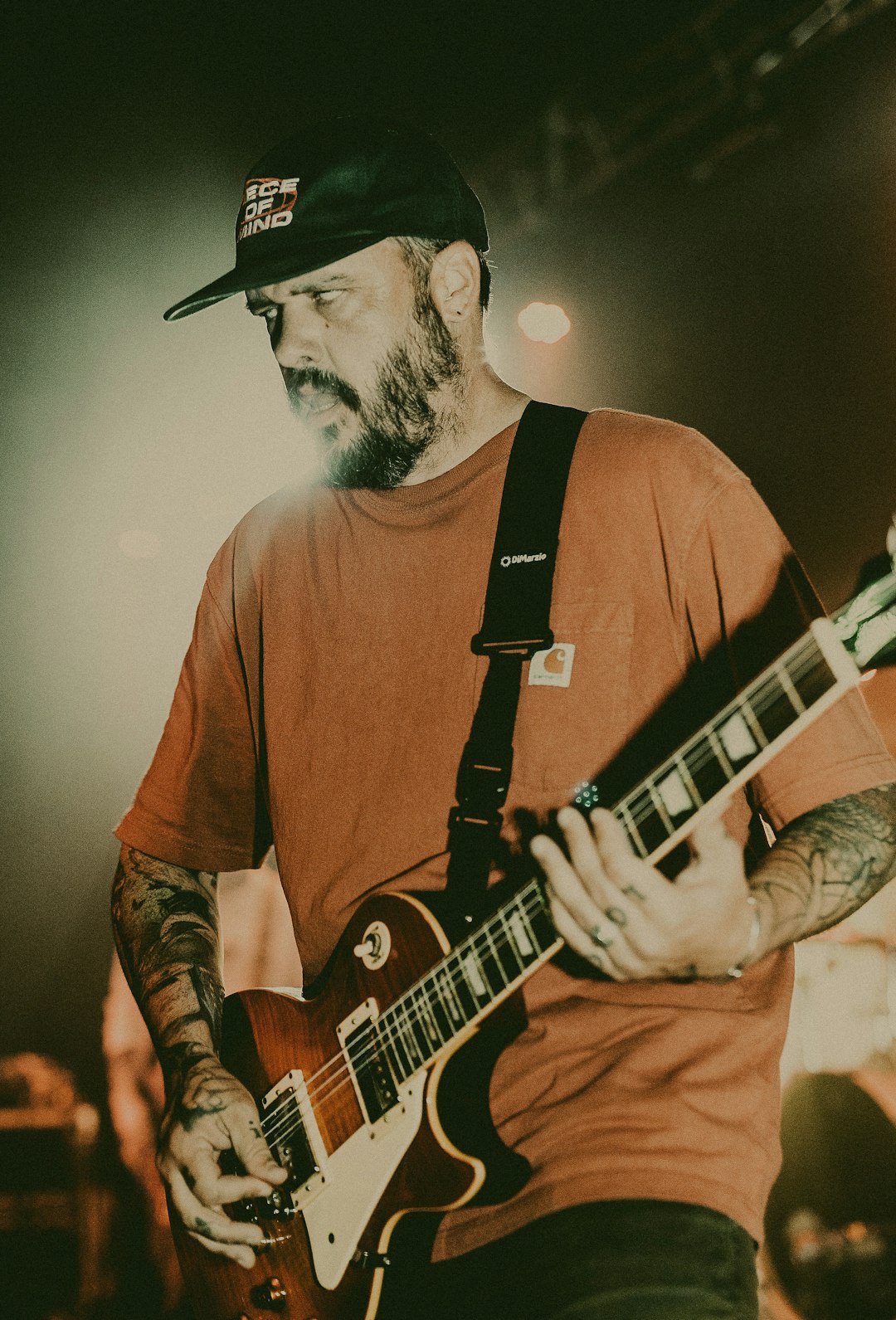 man holding brown and white Les Paul-style electric guitar