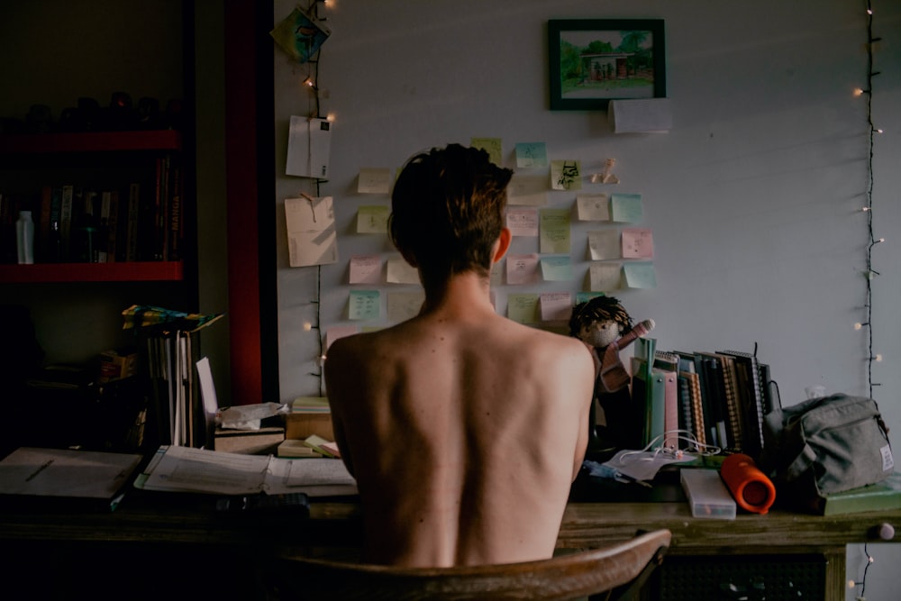 topless man sitting and facing table