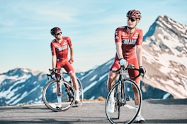 two men biking on road viewing mountain von Hannes Glöckl (https://unsplash.com/@malojapushbikers)