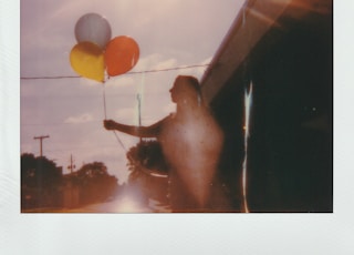 photo of a women holding three balloon close-up photography