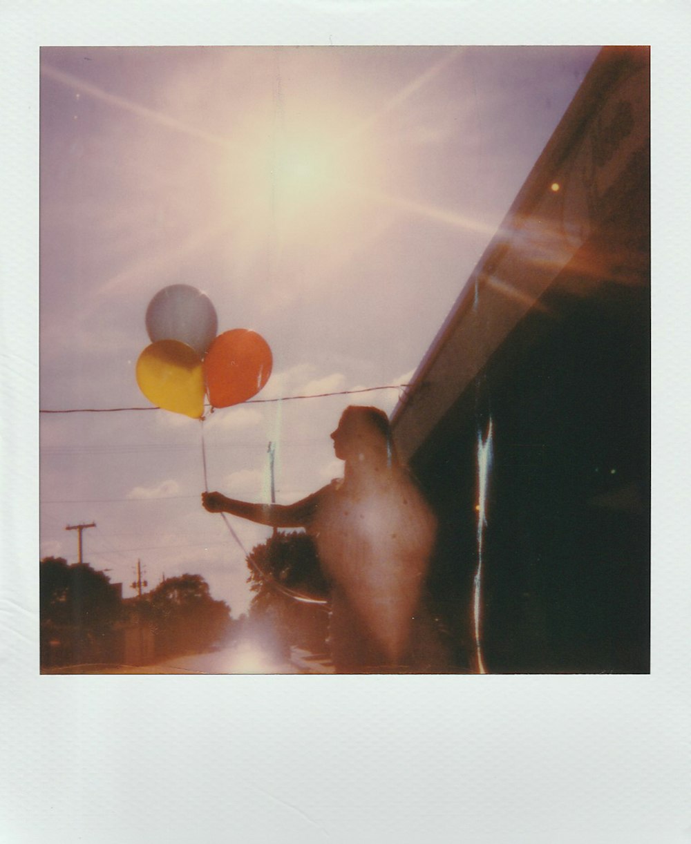 photo of a women holding three balloon close-up photography