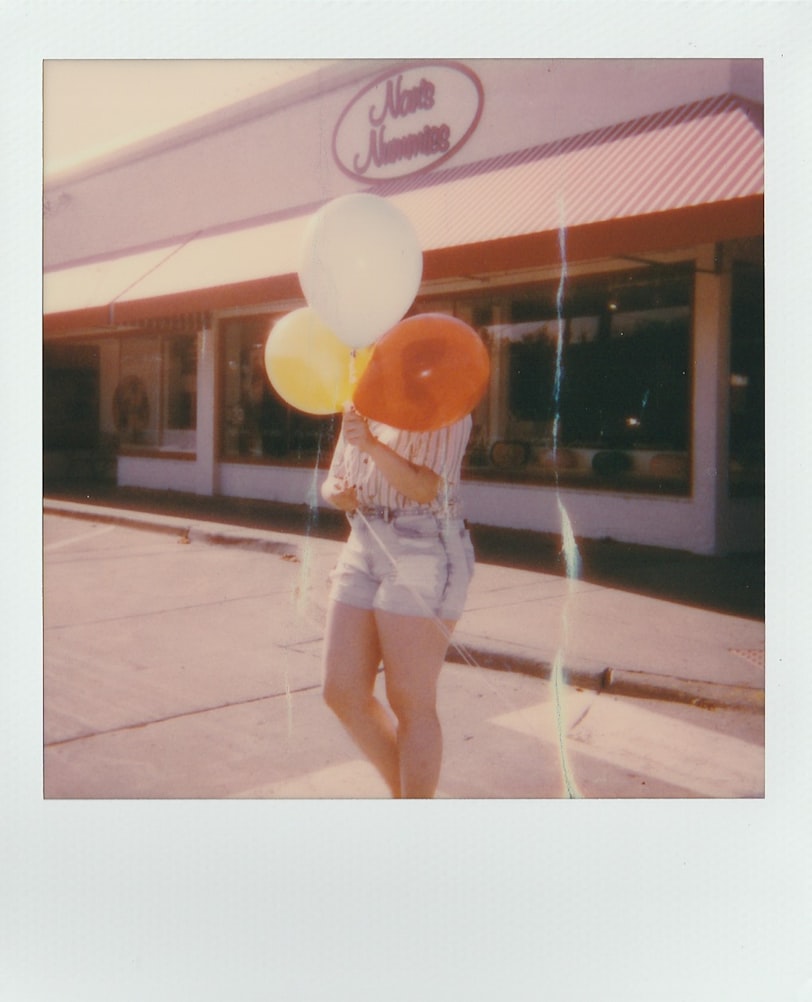 polaroid of woman holding balloons