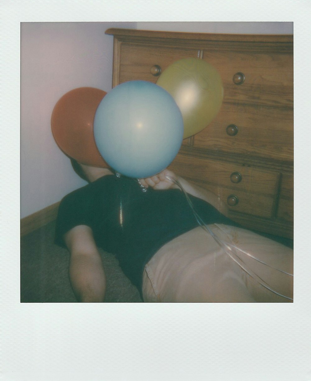 man holding three assorted-color balloons