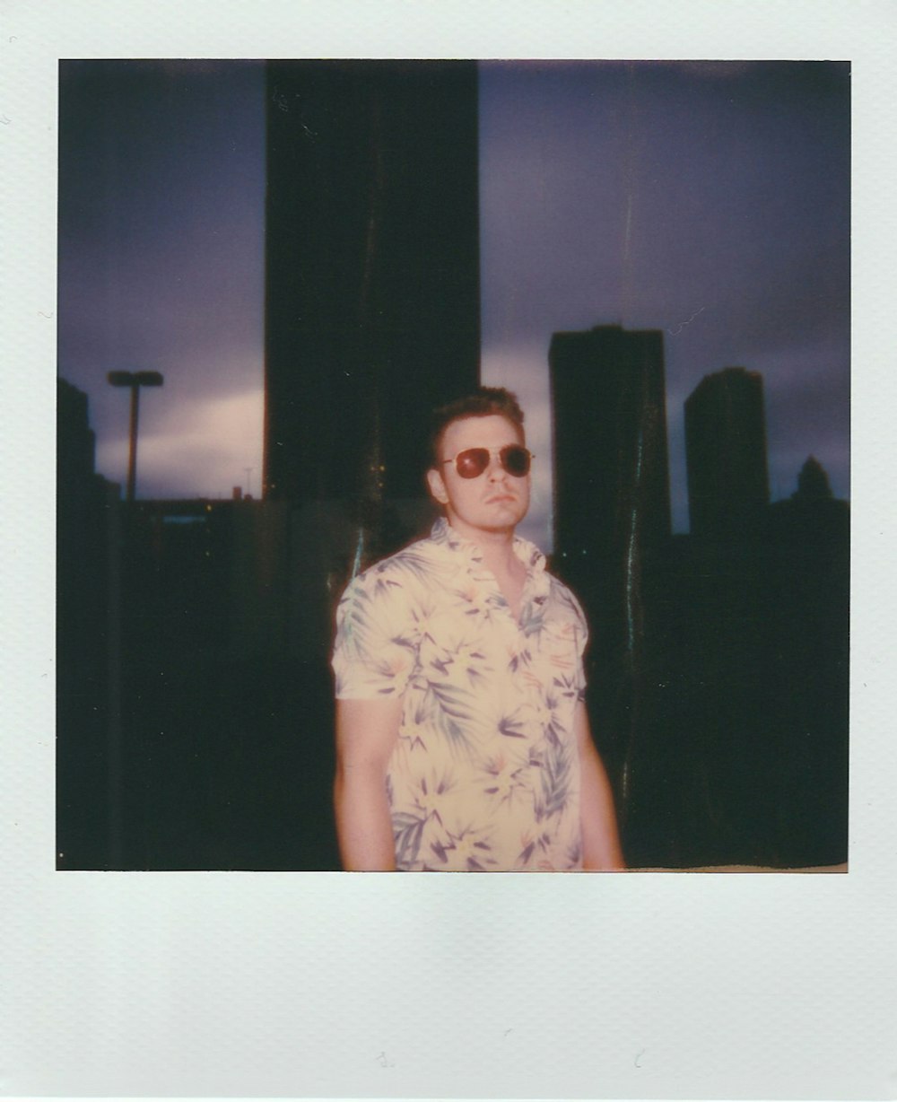 man wearing aviator sunglasses across city building