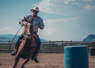 man in white cowboy hat riding a horse