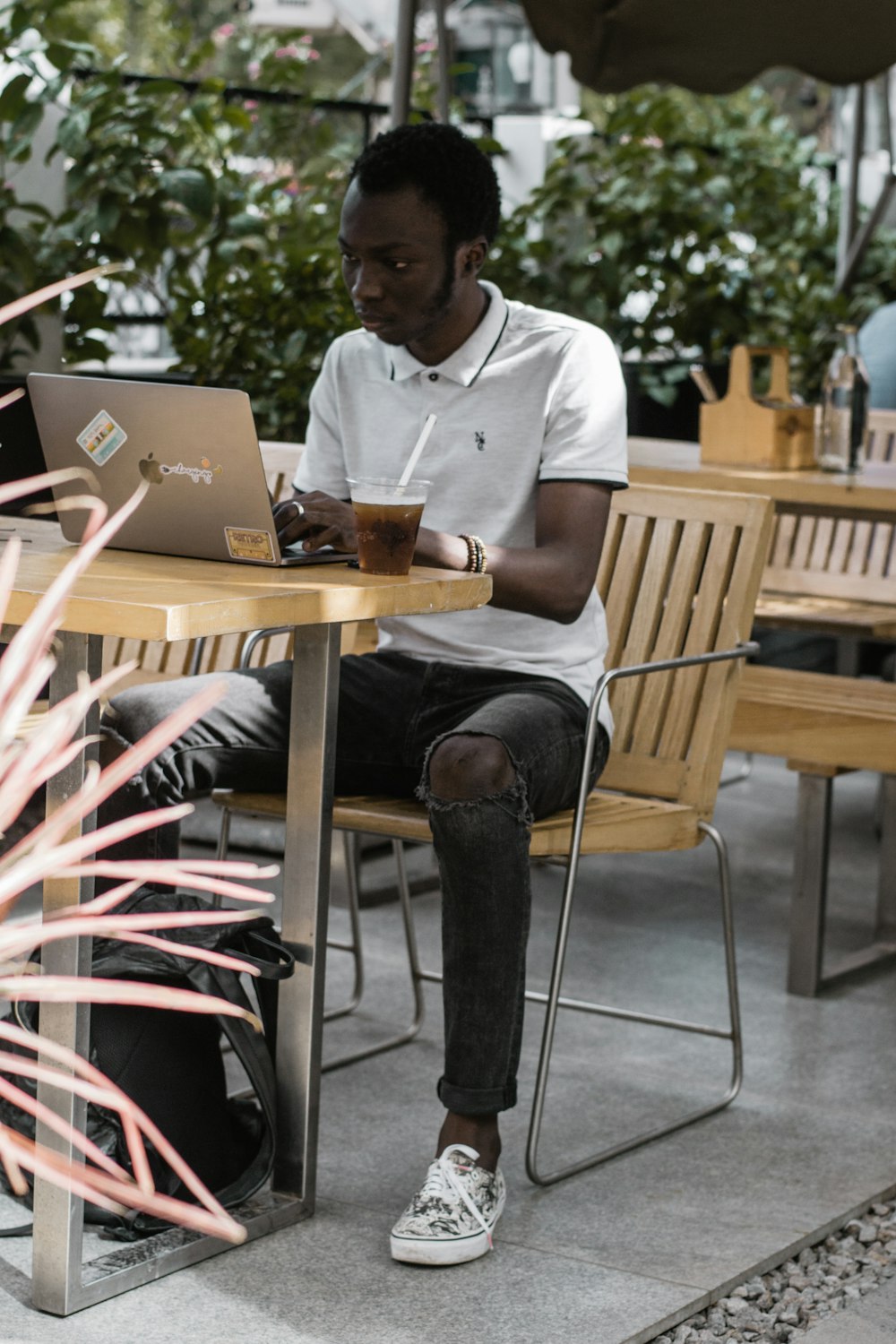 man in white polo shirt sitting on brown wooden chair