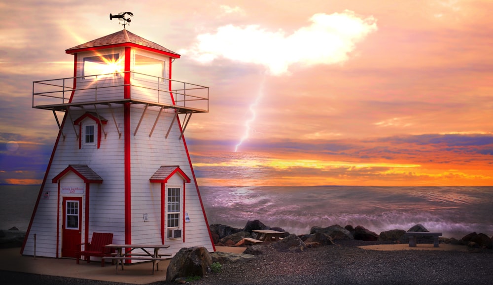 white and red lighthouse by the sea at daytime