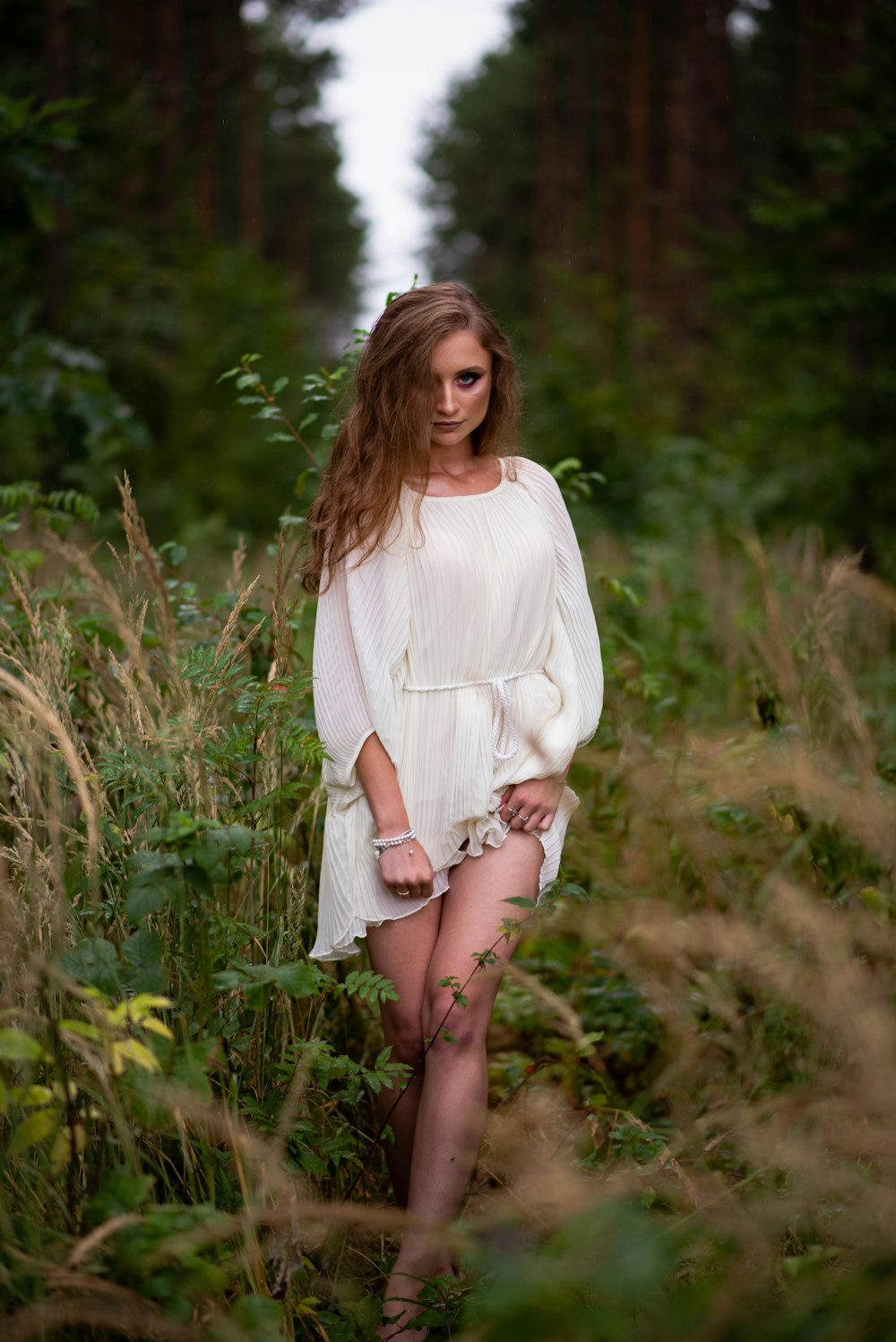 woman wearing white dress walking on tall grasses