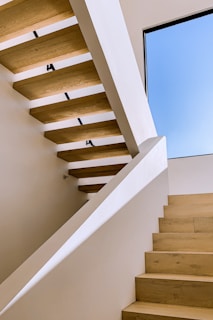 A sophisticated staircase featuring minimalist railing and natural wood steps complementing a bright interior.
