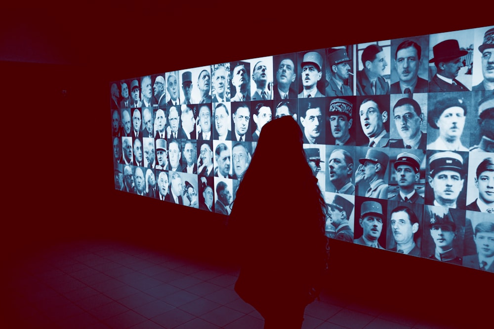 a woman standing in front of a wall with many pictures on it