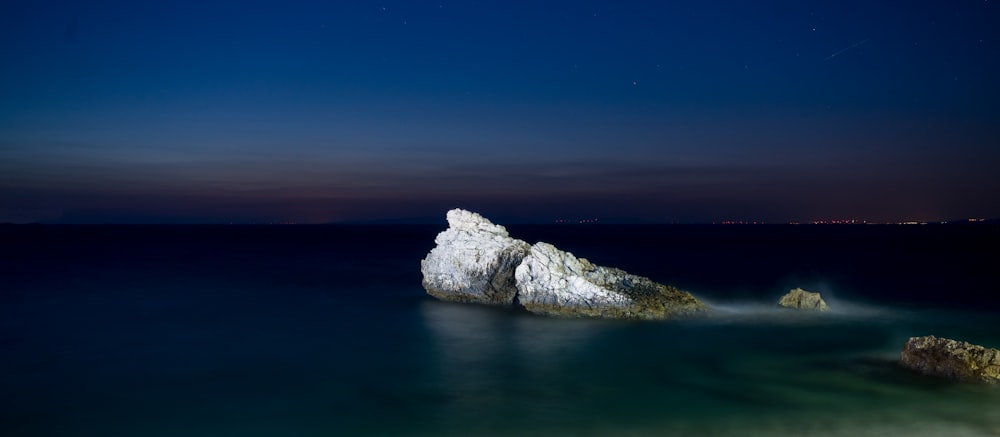 photography of rock formation in body of water during nighttime