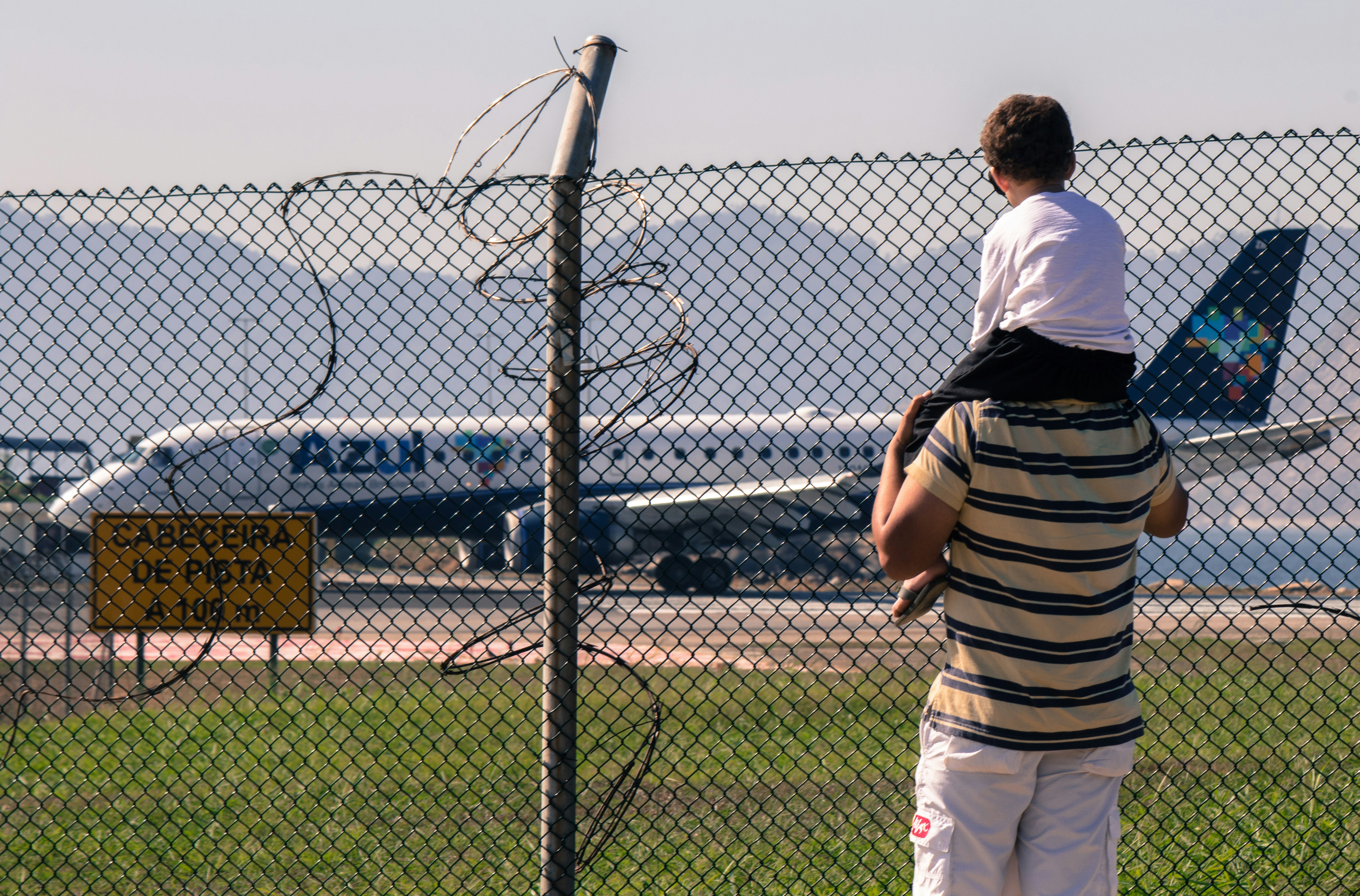 man carrying boy facing white passenger plane