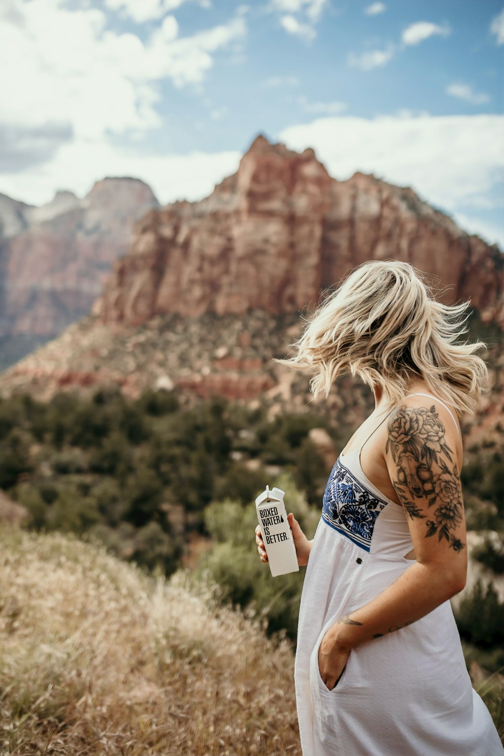woman holding 500 mL of Boxed Water at the mountain